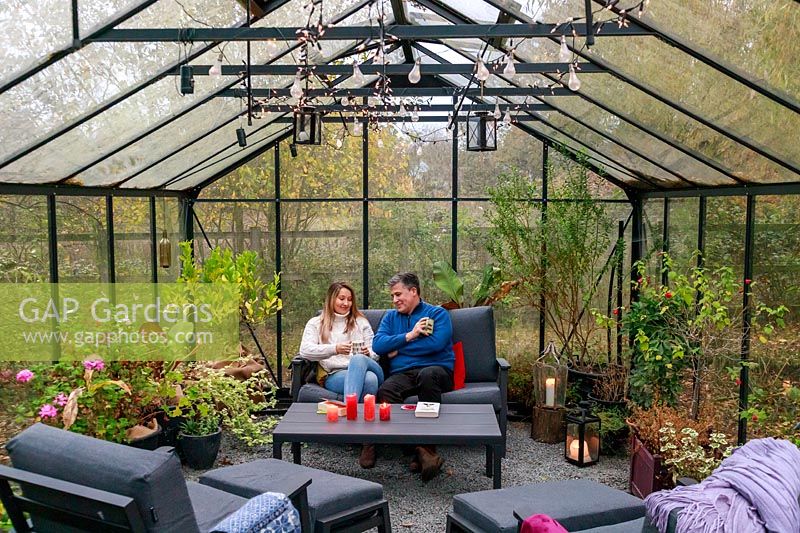 Father and daughter relaxing in lounge furniture in greenhouse in late November