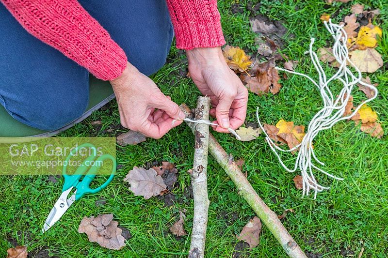 Woman using lengths of twine to tie together the ends of Hazel sticks to form the star shape