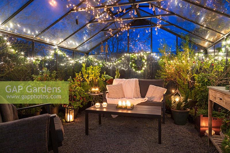Lounge furniture inside greenhouse decorated for Christmas with fairy lights and candles