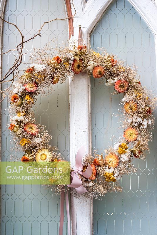 Dried  flower wreath displayed on old door with everlasting flowers and sea lavender