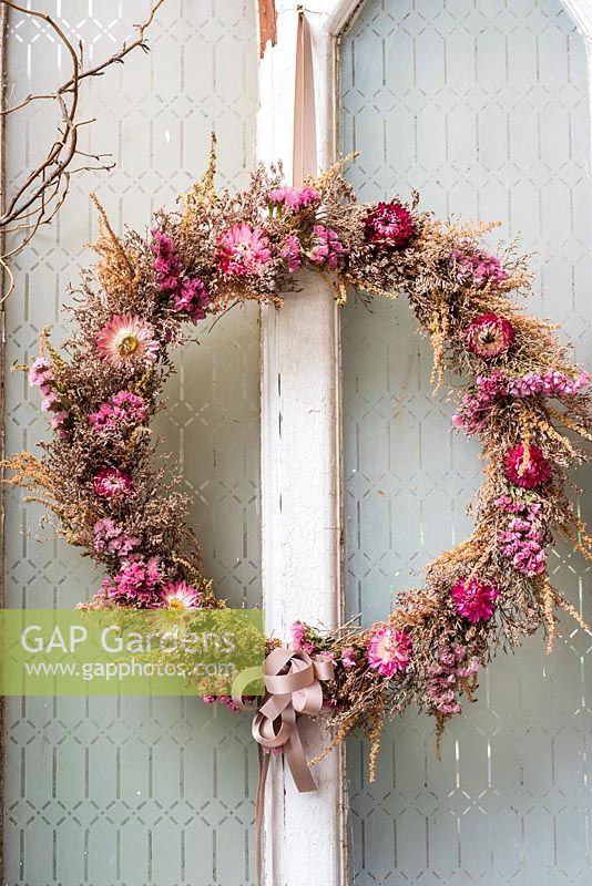 Dried flower wreath displayed on old door with everlasting flowers and sea lavender