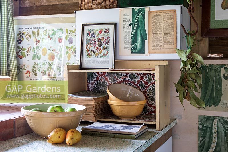 Old fashioned vintage kitchen area for vegetable preparation in garden room, filled with gardening paraphanalia and vintage wall art