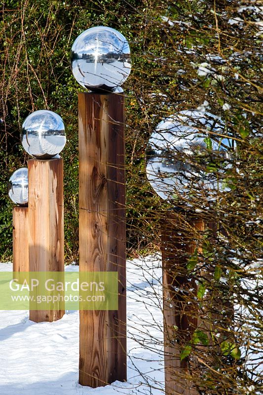 Line of wooden posts topped with stainless steel globes. Garden - Veddw 