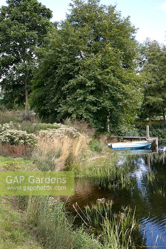 View across the lake to the landing stage in a private garden at Brockhampton open for NGS