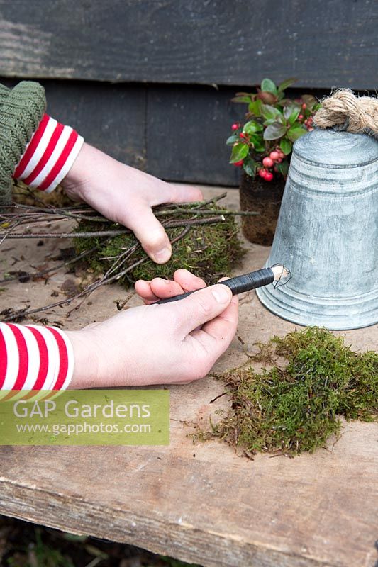 Woman wiring twigs to the moss covered floral oasis Styling by Marieke Nolsen. 