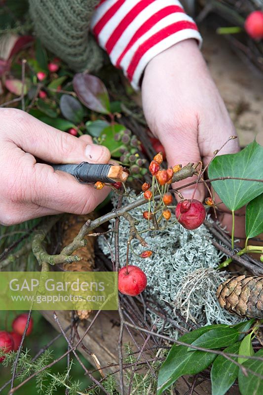 Woman wiring berries to the rustic wreath. Styling by Marieke Nolsen. 