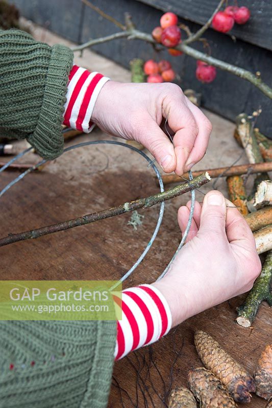 Woman creating wooden globe using Birch sticks and wire to fix to stand. Styling: Marieke Nolsen