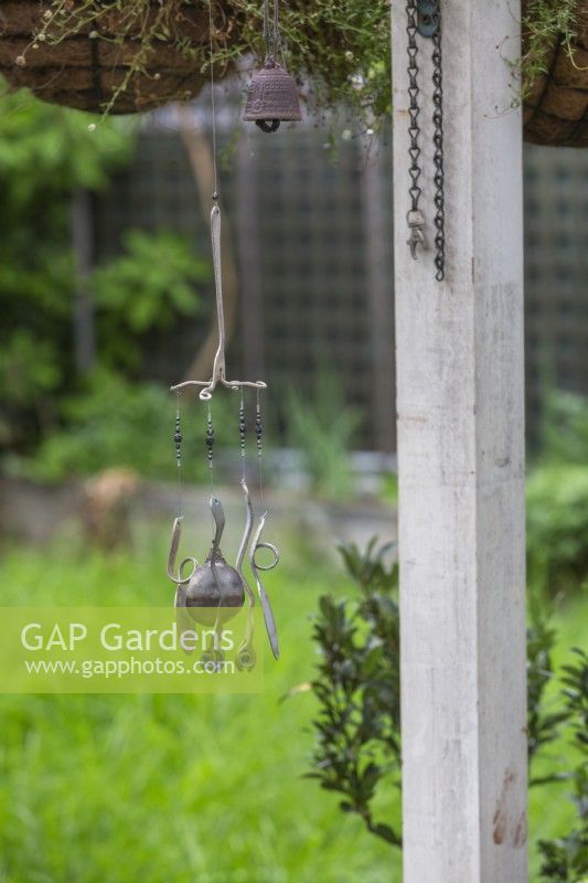 A handmade windchime made from repurposed forks and spoons and blue glass marbles