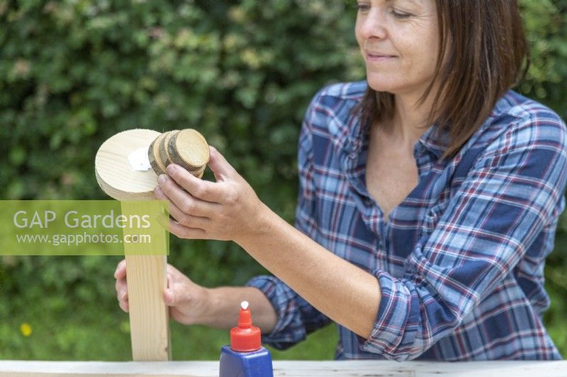 Woman gluing stack of wooden discs to the end of the post