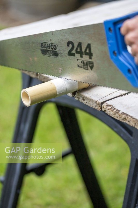 Sawing pieces of bamboo to desired length through masking tape to prevent splintering
