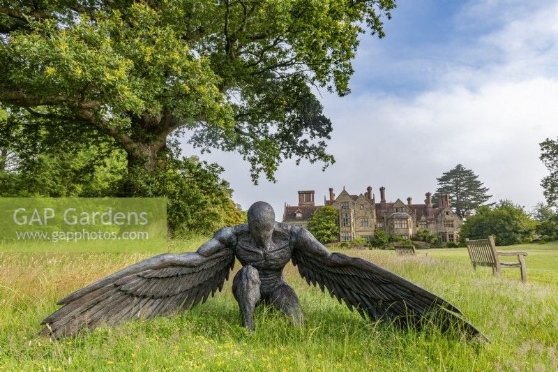 Sculpture of a bronze angel kneeling on a lawn in summer - July