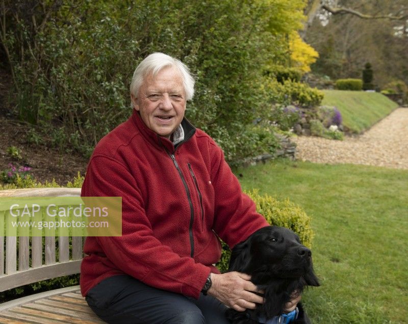 Man in jacket sitting on bench near pet dog