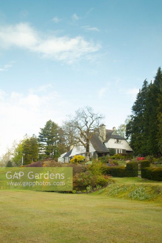 A lawned area in front and herbaceous borders around the Arts and Crafts style house at High Moss