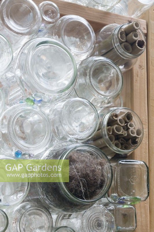 Nesting materials for birds are tucked into outward facing glass jars in recycled greenhouse walls. Bamboo pieces offer habitat for pollinating insects