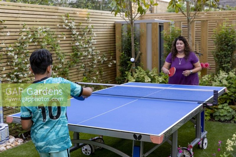 Mother playing table tennis with her son their West London garden