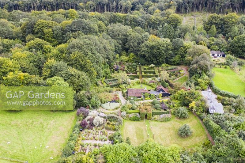 View over whole garden with house in centre and out to surrounding woodland; image taken with drone. September. Summer.