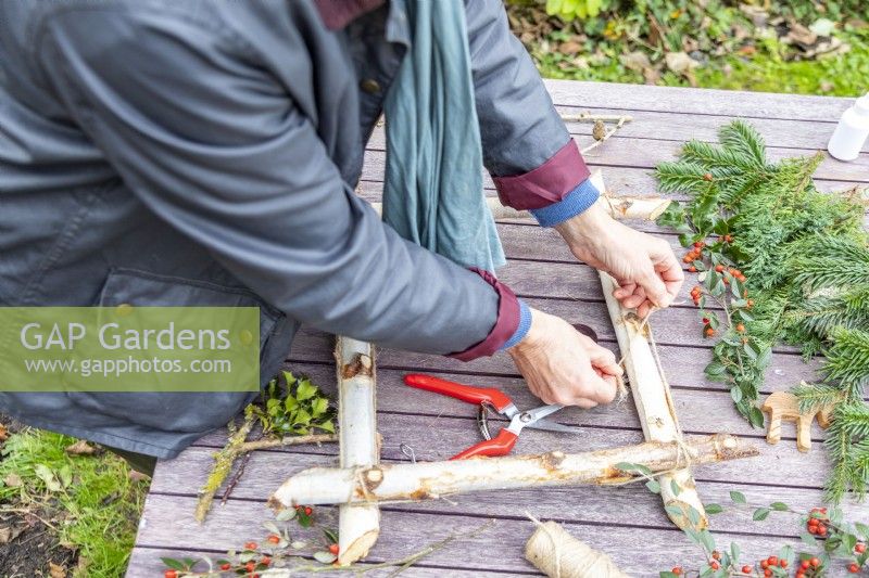 Woman tying the four birch sticks together
