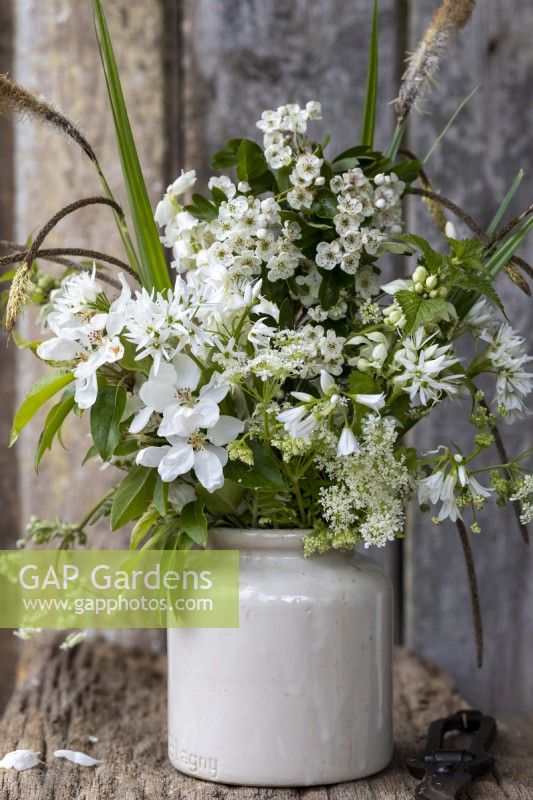 Simple posy of white and green in an old ceramic pot. Rustic setting.
