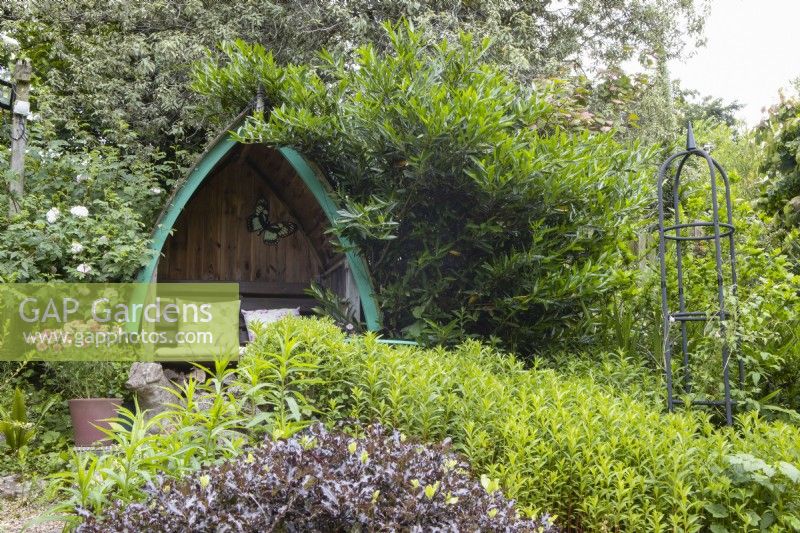 A half boat seating area in a cottage style garden by the coast in Devon. July. Summer. 