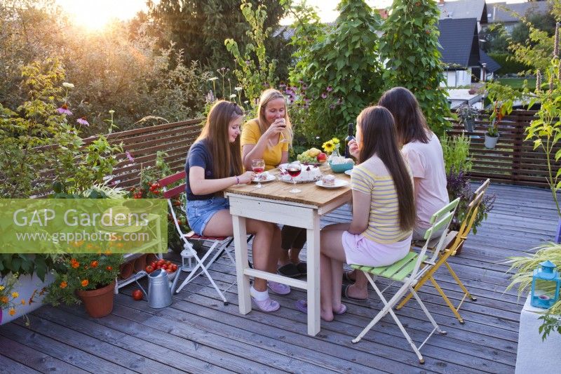 Women sat enjoying cake and drinks on roof terrace.