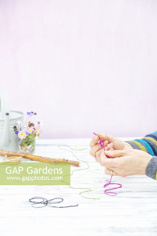 Woman tying the ends of each piece of coloured string together