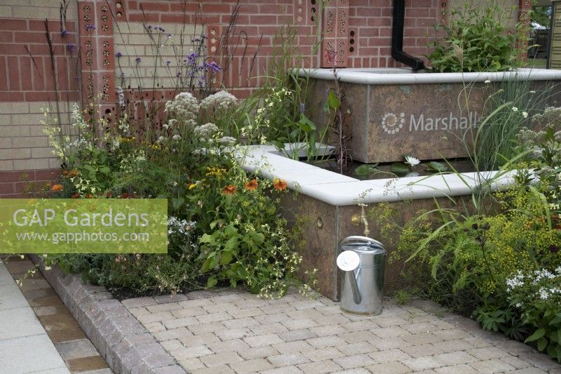 'The Marshalls Garden' at BBC Gardener's World Live 2021 - urban garden with raised two tier pond bordered by decorative brick wall with built in insect hotels 