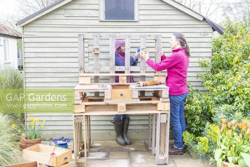 Woman screwing blocks to the back of the bench to use as brackets for the shelf