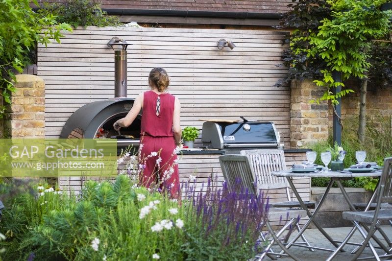 Lisa, garden owner baking pizza in the outdoor pizza oven. 