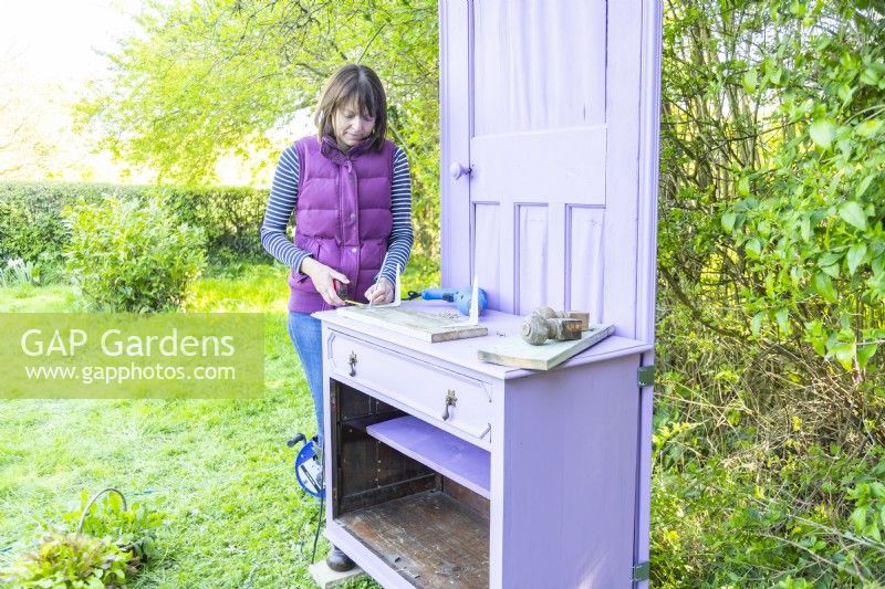 Woman marking location for the shelf brackets