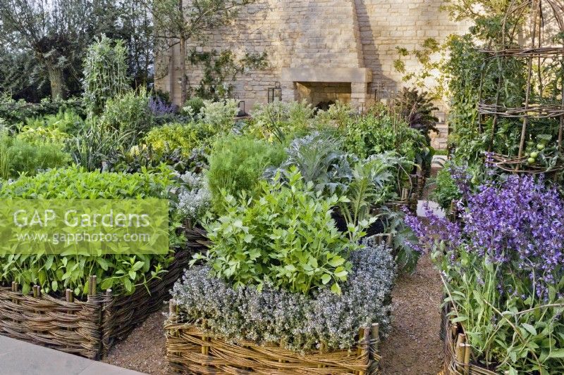 'Summer Solstice' Daylesford Organic. Design by del Buono Gazerwitz. Silver-Gilt RHS Chelsea Flower Show 2008. Organic agrarian potager garden.
Small wicker fenced beds with a large variety of herbs and vegetables for the kitchen. Cotswold stone wall with outdoor fireplace.