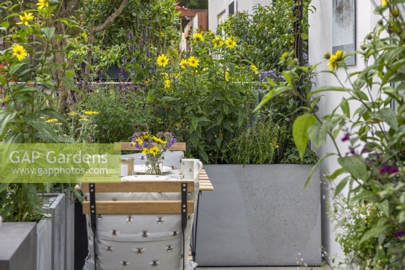 Small balcony garden with a patio table and chair's, flower posy, metal planters with Hyssop officinalis, Salvia 'Nachtvlinder', Achillea 'Moonshine' yarrow, Helianthus 'Lemon Queen' and Nepeta 'Blue Cloud'.

The Landform Balcony Garden 

Designer: Nicola Hale 

Category: Balcony Garden

RHS Chelsea Flower Show 2021