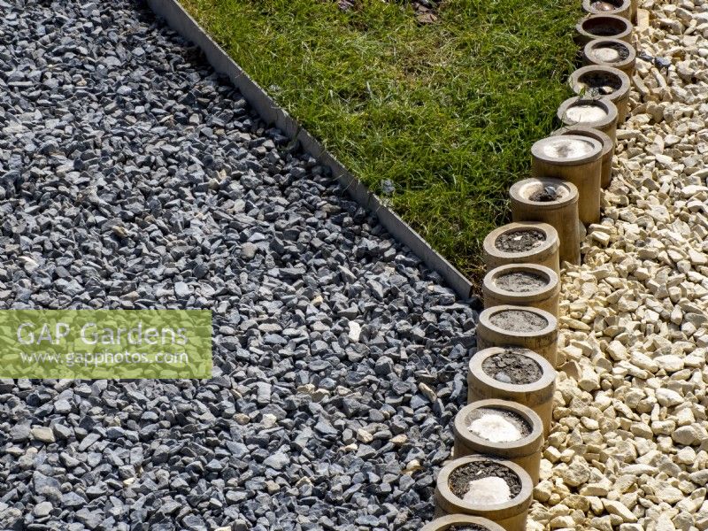 Edging detail of thick stemmed bamboo tubes separating two colours of gravel pathway and lawn. Floriade Expo 2022 International Horticultural Exhibition Almere Netherlands