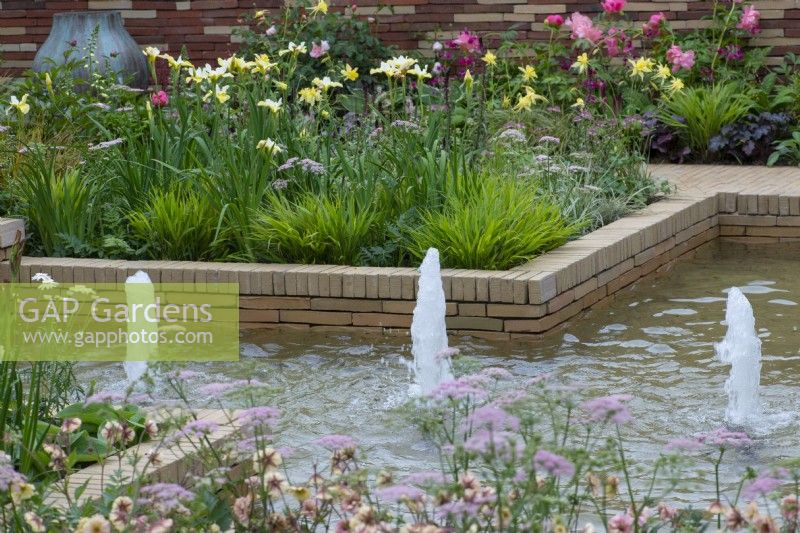 A sunken pool with fountains is edged in herbaceous beds planted with a tapestry of irises, peonies, pimpinella, geums and ornamental grasses.