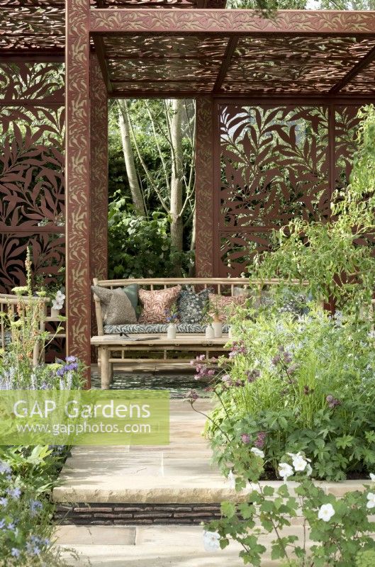 William Morris Willow Boughs design inspired metal pavilion amidst romantic garden planting