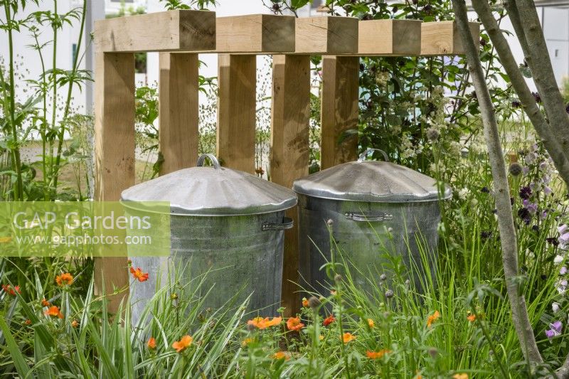 Wooden enclosure for metal compost bins hidden under wooden slots and planting - The Core Arts Front Garden Revolution Garden