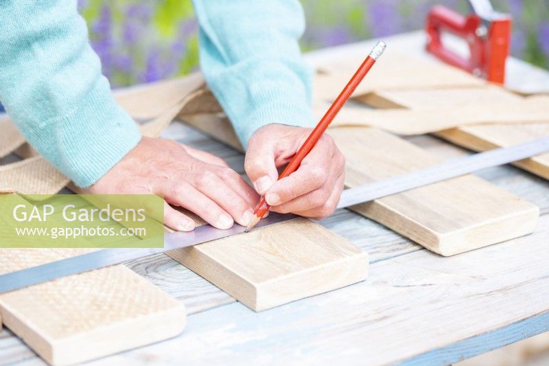 Woman marking a guiding line for attaching the burlap to the planks