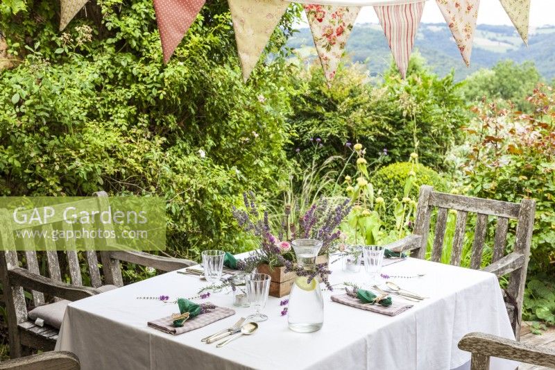 Terrace with set table and chairs, bunting decorated with lavender and other flowers - Lavender summer party story