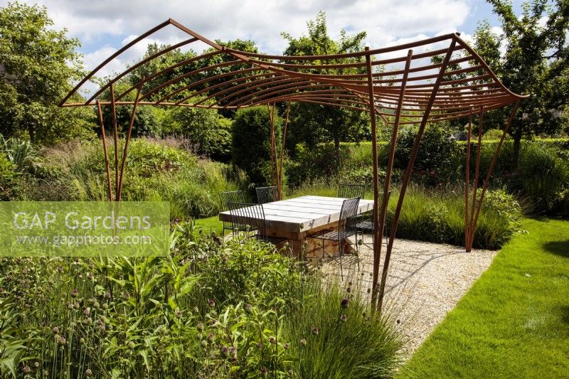 An artisinal wrought iron pergola designed and made for an outdoor living space by artist blacksmith Paul Elliot in a private garden.