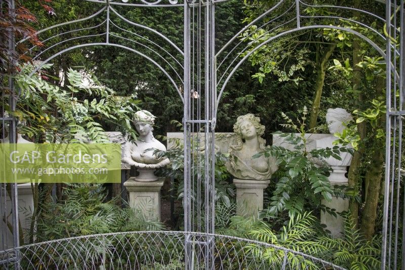 Classical busts behind the gazebo at Hamilton House garden in May 
