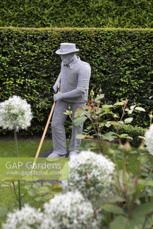 Wire sculpture of a man gardening by Derek Kinzett in the front garden at Hamilton House garden in May 