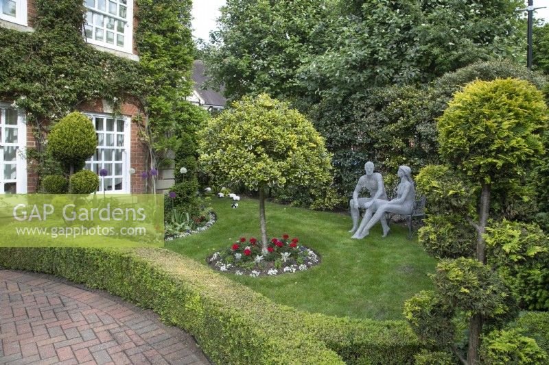 Front garden with wire sculptures by Derek Kinzett and cloud trees at Hamilton House garden in May 