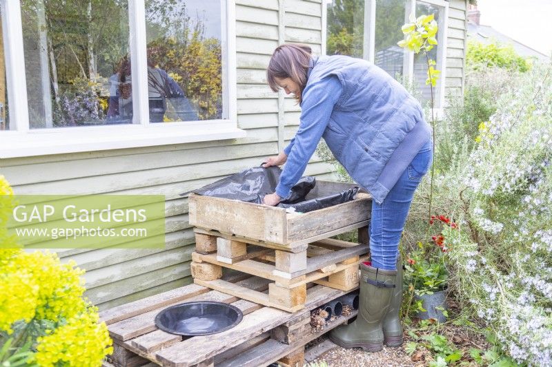 Woman placing liner in the top of the pallet bug hotel