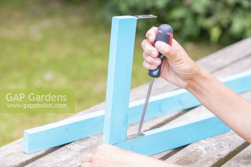 Woman screwing pieces of wood together with brackets