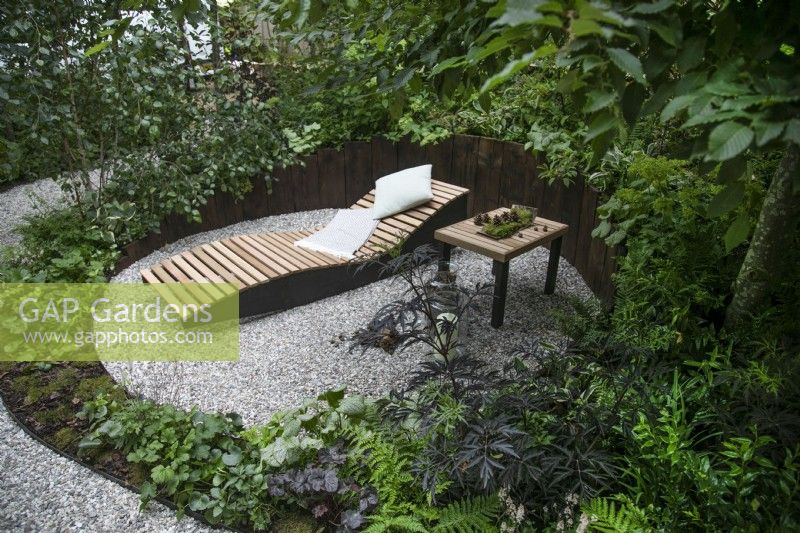 Seating area in dappled shade in the RHS Forest Bathing garden at the RHS Hampton Court Palace Garden Festival 2022