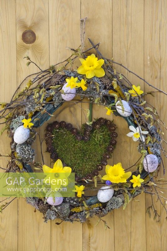 Hanging moss heart and Easter wreath made of branches, lichens and coloured eggs.