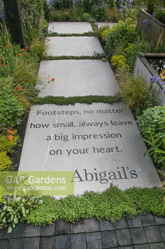 Path with message bordered by perennials in Abigail's Footsteps Garden at RHS Malvern Spring Festival 2022