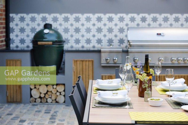 Table set up for a dinner by outdoor kitchen. 