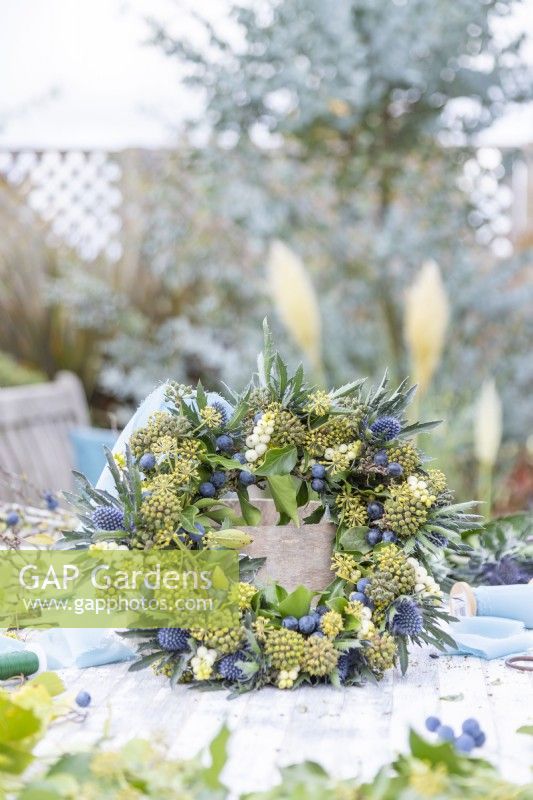 Ivy, Symphoricarpos and Eryngium wreath on wooden table