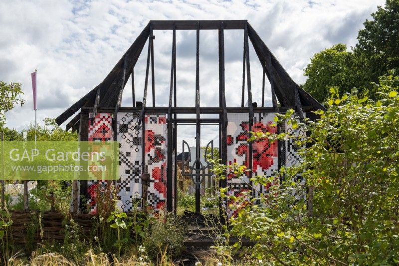 Representation of a Ukranian burnt cottage draped with rushnyk, an embroidered cloth.  What Does Not Burn - RHS Hampton Court Palance Garden Festival 2022
