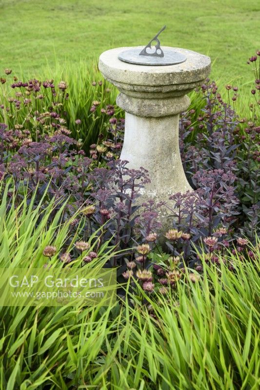 Sundial surrounded by Hakonechloa macra, Hylotelephium 'Jose Aubergine' and astrantias at Cow Close Cottage, North Yorkshire in July